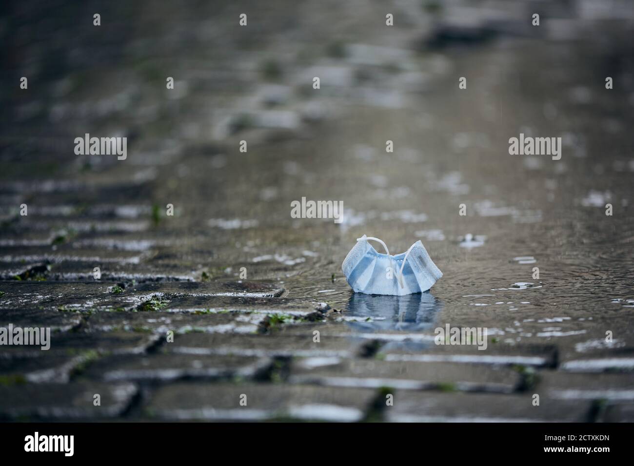 Utilisé masque jetable dans le bas de la porte pendant la pluie. Thèmes coronavirus problèmes et la vie dans la nouvelle normale. Banque D'Images