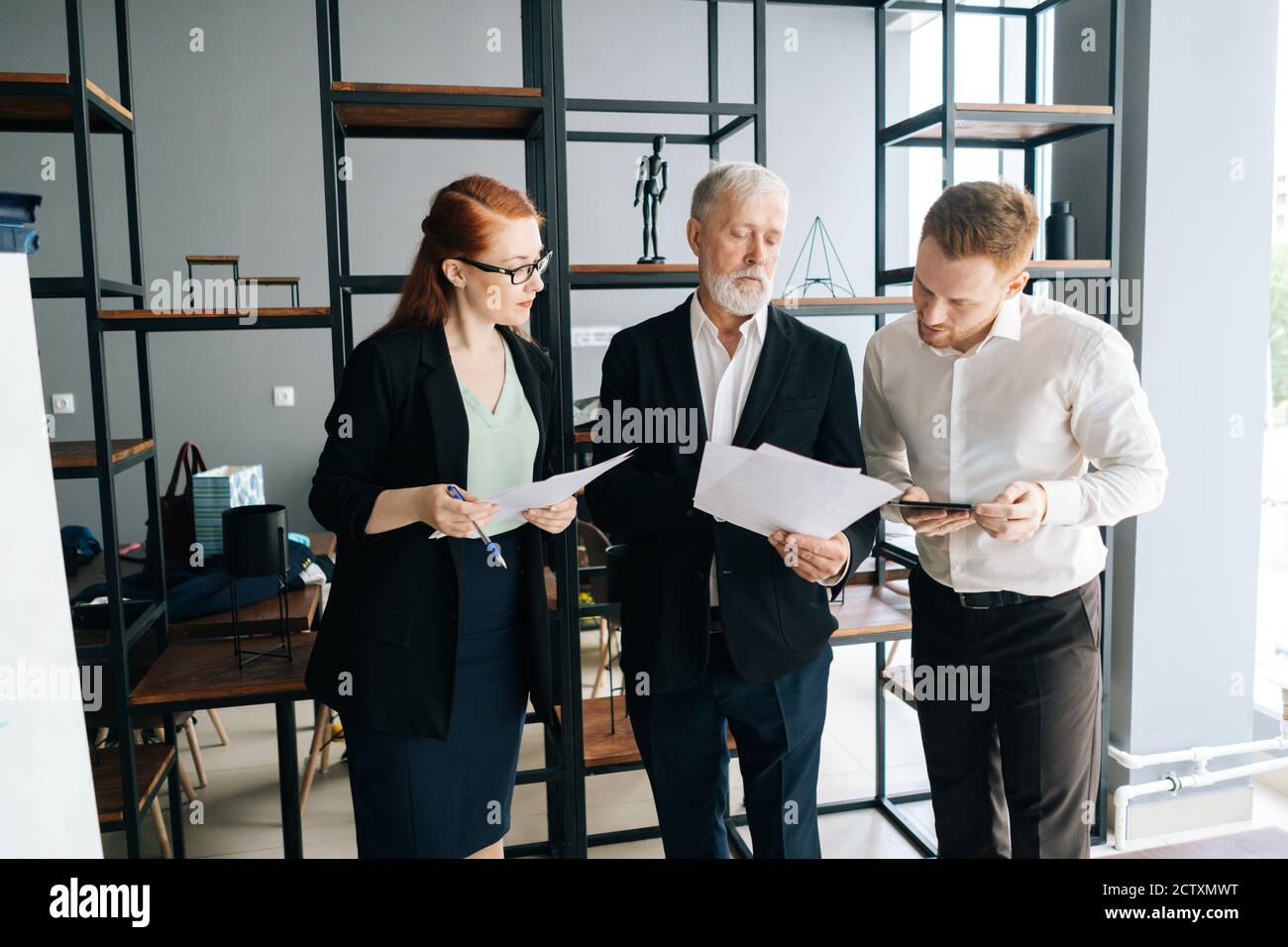 Une équipe professionnelle motivée qui étudie les tablettes numériques et les documents de discussion. Banque D'Images