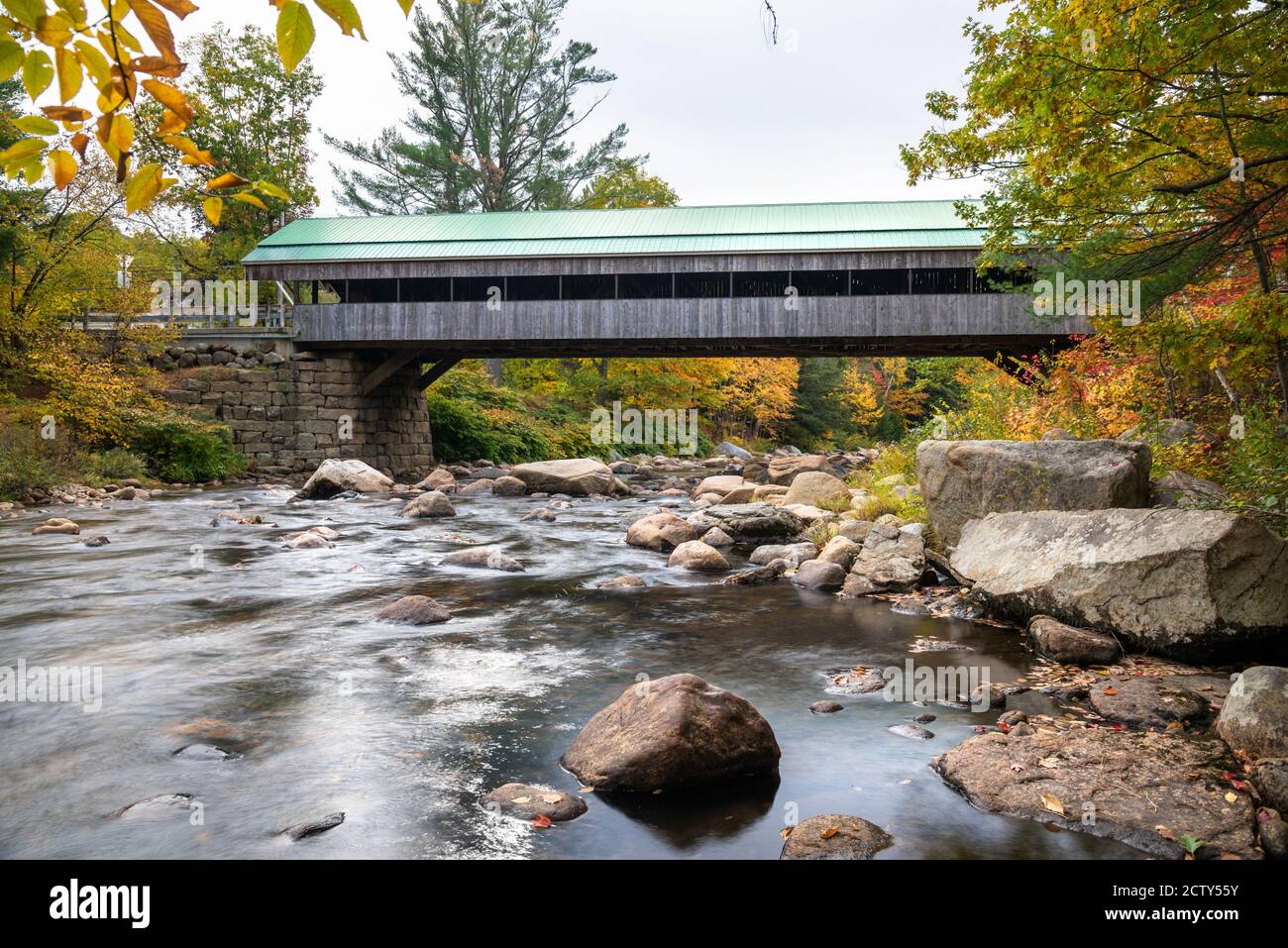 La Nouvelle-Angleterre historique a couvert un pont au-dessus d'une rivière de montagne lors d'une journée d'automne nuageux. Superbes couleurs d'automne. Banque D'Images
