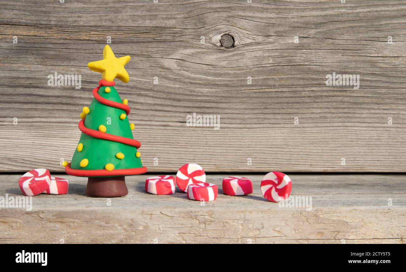Concept de Noël ludique. Miniature artisanale colorée. Arbre de Noël en terre battue devant un fond en bois doux. Copier l'espace Banque D'Images