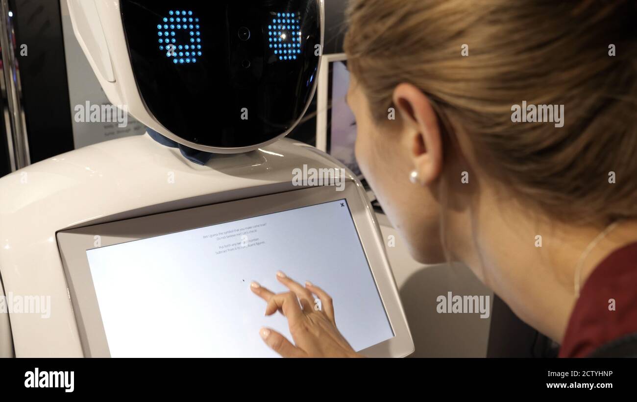 Robot humanoïde avec écran tactile face parlant avec la femme. Banque D'Images