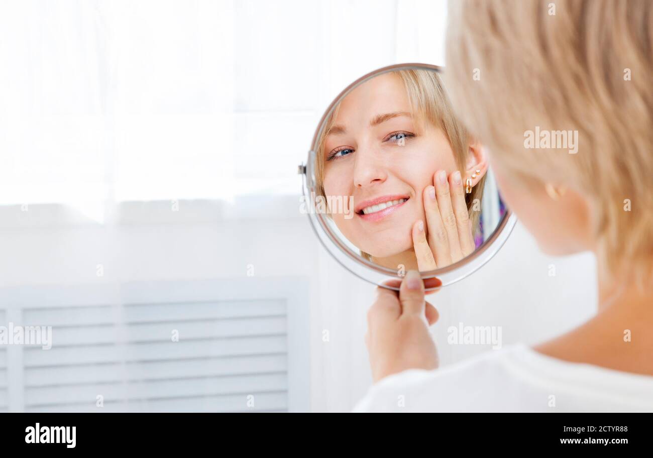 Belle femme regardant dans le miroir le matin et sourire Banque D'Images