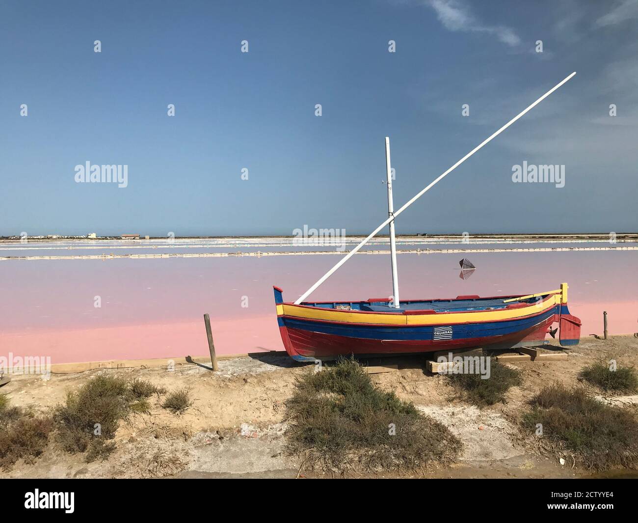 Le bateau coloré en face du marais salé aussi coloré des salines à Gruissan, dans le sud de la france Banque D'Images