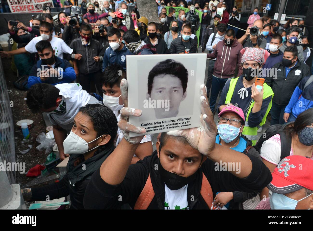 MEXICO, MEXIQUE - SEPTEMBRE 25 : une personne lève une photo d'un étudiant disparaît alors qu'une fresque commémore le 6e anniversaire des 43 élèves de l'école normale qui ont disparu le 26 septembre 2014. Les parents des 43 élèves d'Ayotzinapa lors d'une manifestation à l'extérieur du Procureur général de la République pour demander justice aux 43 élèves de l'Ecole normale rurale 'Raul Isidro Burgos' d'Ayotzinapanon 25 septembre 2020 à Mexico, Mexique. Crédit : Carlos Tischler/Eyepix Group/The photo Access Banque D'Images