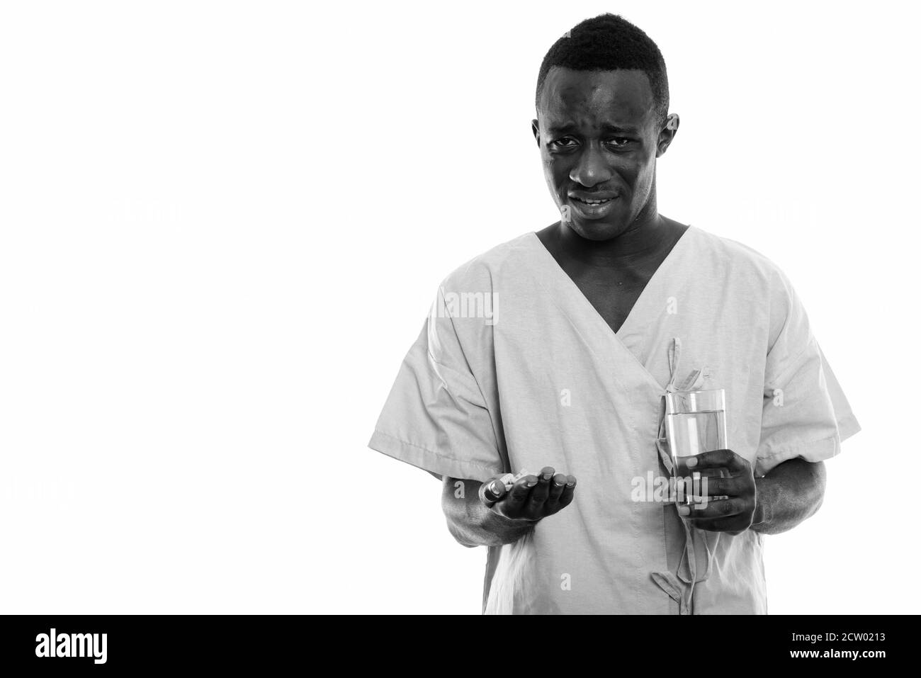 Portrait de jeune homme de l'Afrique noire à la patiente les comprimés de vitamine en maintenant dégoûté et verre de l'eau Banque D'Images