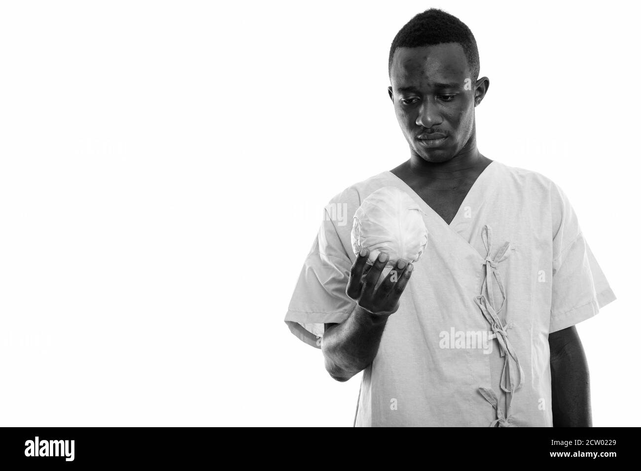 Studio de prise de vue d'un jeune homme africain noir patient tenant et regarder le chou Banque D'Images
