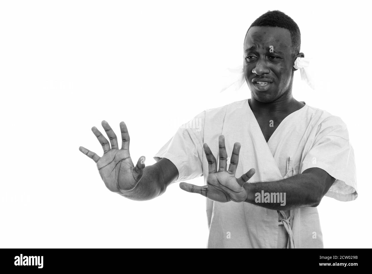 Jeune Africain homme patient malade avec des tissus dans son les oreilles et le panneau stop avec les deux mains Banque D'Images
