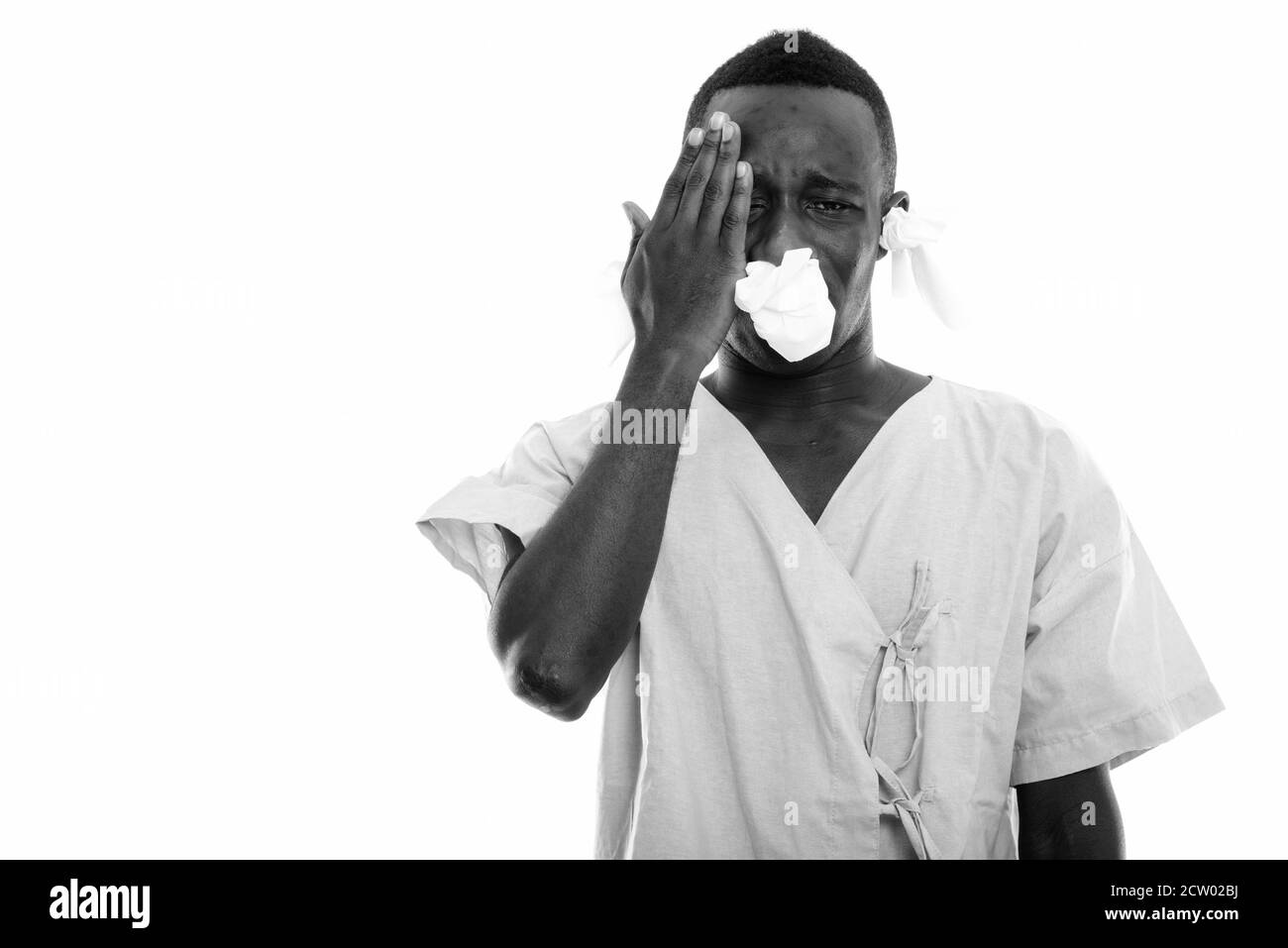 Studio shot of young black African man patient ayant des maux de tête et à la malade de tissus dans ses oreilles et nez Banque D'Images