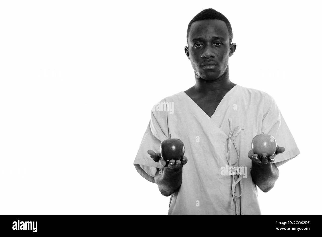 Photo en studio d'un jeune homme africain noir, patient tenant deux pommes Banque D'Images