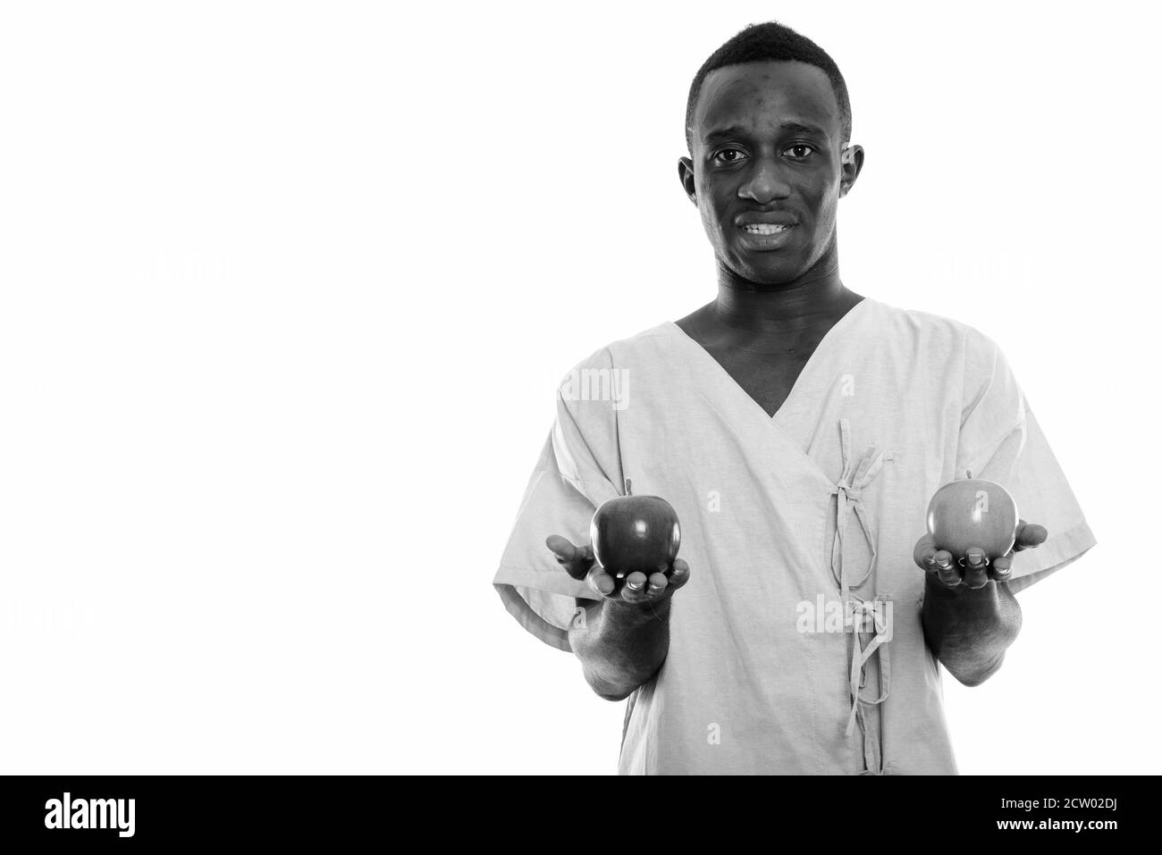 Photo en studio d'un jeune homme africain noir heureux tenant un patient deux pommes Banque D'Images