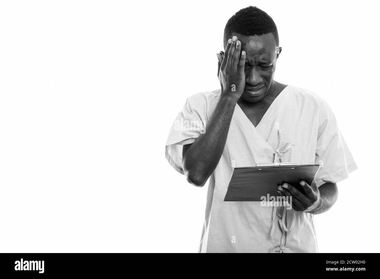 Studio shot of young black African man reading patient sur presse-papiers alors que la recherche a souligné Banque D'Images
