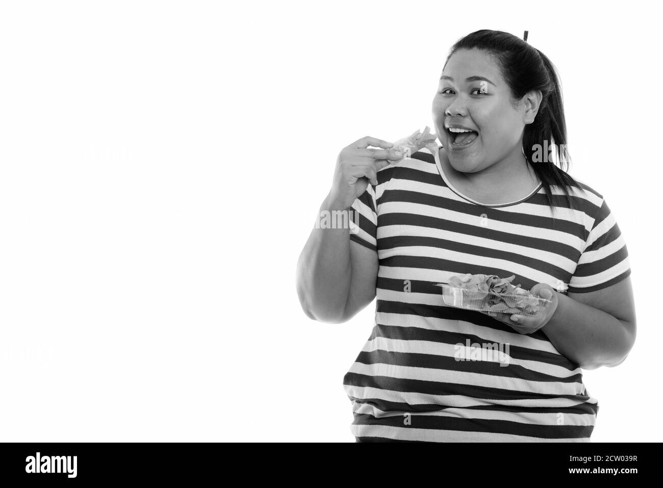 Studio shot of young woman smiling Asian fat heureux en mangeant des légumes frais wrap Banque D'Images