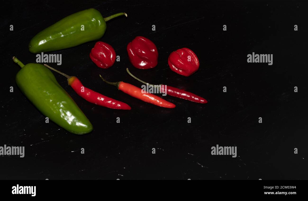 Plaque d'ardoise de différents types de poivrons rouges et verts tels que Serenade, Chili, jalapeños, Chelles, Naga, Habanero, Scorpion Banque D'Images