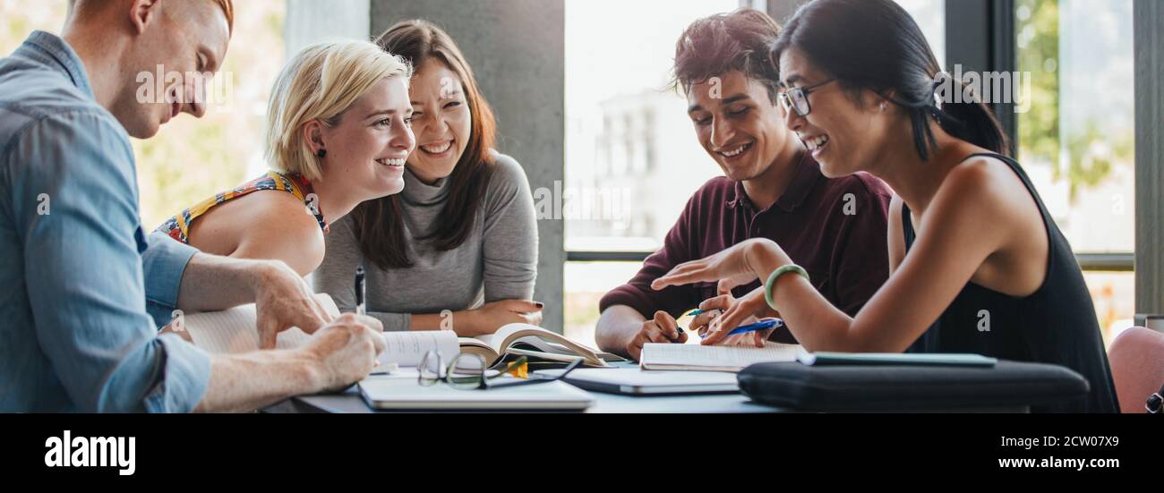 Heureux les jeunes étudiants universitaires avec des livres en bibliothèque. Groupe de personnes dans la bibliothèque du collège multiraciale. Banque D'Images