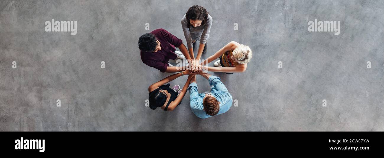 Les jeunes qui se mettent la main l'un sur l'autre symbolisent l'unité et le travail d'équipe. Divers groupes d'élèves se empilent les mains. Banque D'Images