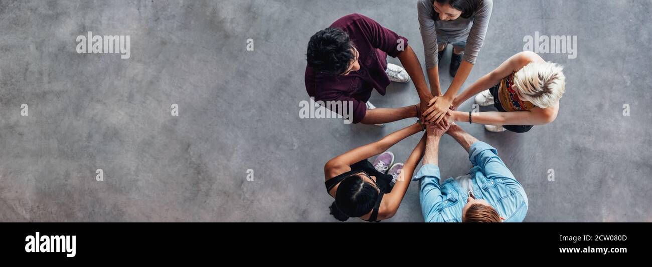 Vue supérieure des jeunes avec les mains sur le dessus de l'autre. De jeunes étudiants de faire une pile de mains. Banque D'Images