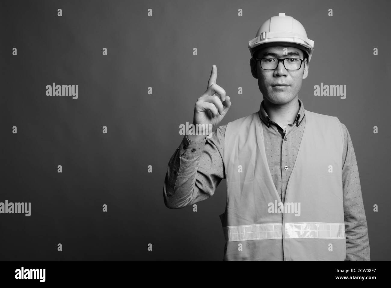 Young Asian man construction worker contre l'arrière-plan gris Banque D'Images