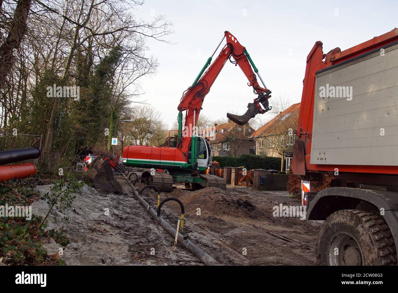 Travaux routiers avec une pelle rouge verte et un camion dans le village néerlandais de Bergen. Pays-Bas. Décembre Banque D'Images