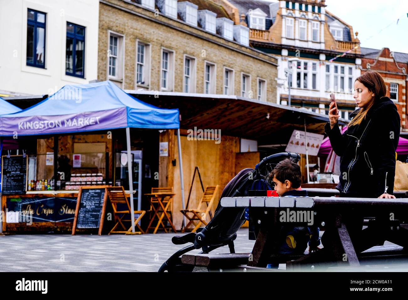 Mère utilisant UN smartphone Track and Trace and son In Une place du marché vide COVID-19 Banque D'Images