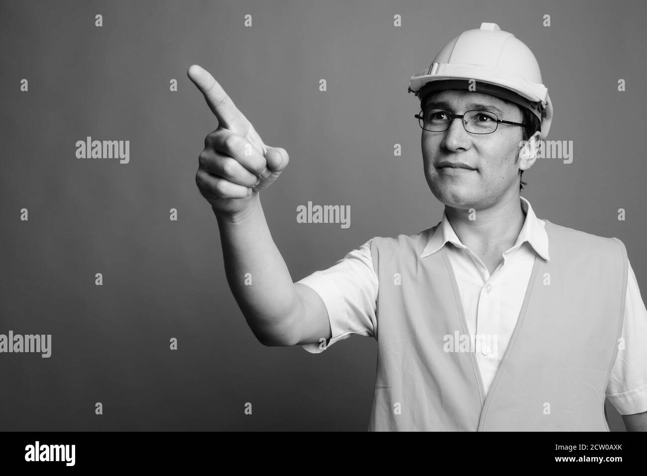Jeune homme asiatique travailleur de la construction portant des lunettes sur fond gris Banque D'Images
