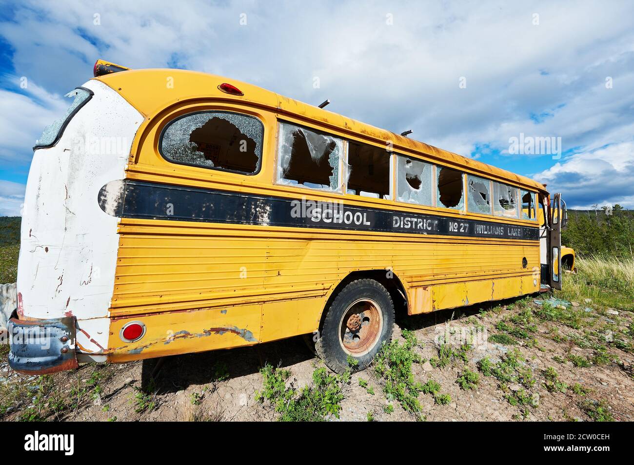 Vieux bus scolaire américain jaune vandalisé avec des fenêtres de verre cassées sur un site de décharge du gouvernement près du lac Chilco, British Vancouver, Canada Banque D'Images