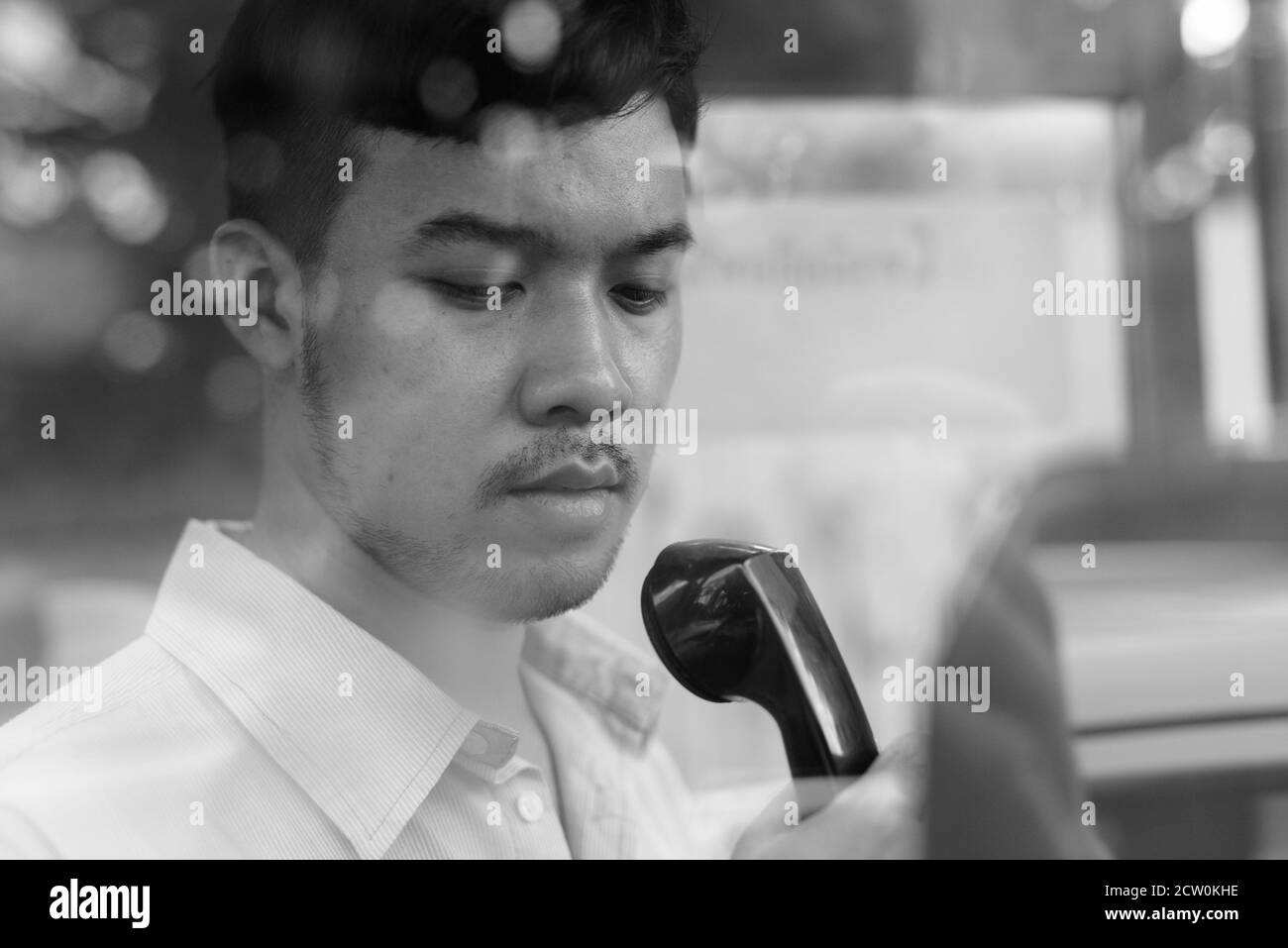 Young Asian businessman en utilisant le téléphone public à l'extérieur Banque D'Images