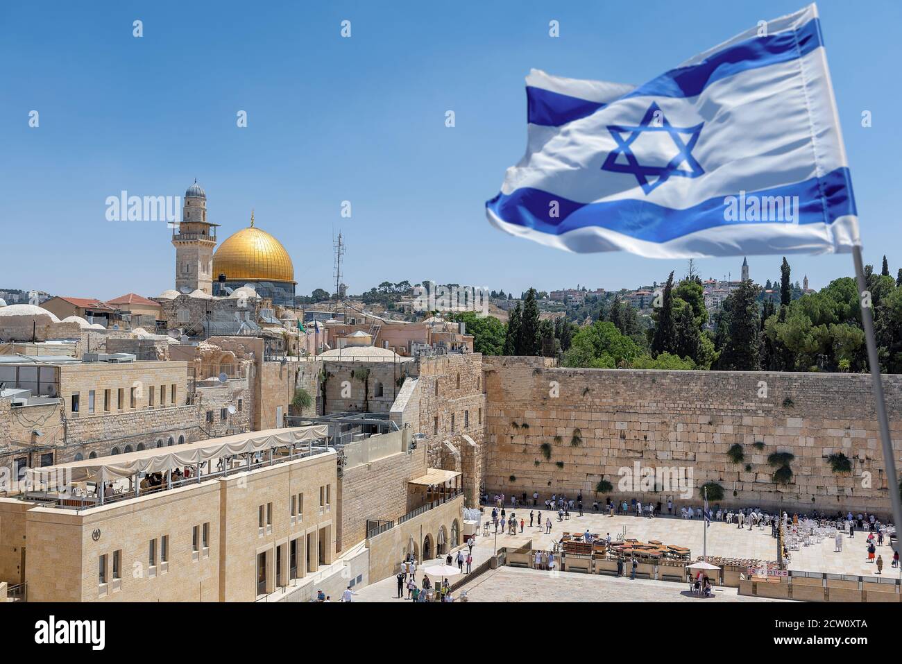 Un drapeau israélien souffle dans le vent tandis que les croyants orthodoxes juifs lisent la Torah et prient face au mur occidental, également connu sous le nom de mur de Wailing ou de Kotel in Banque D'Images