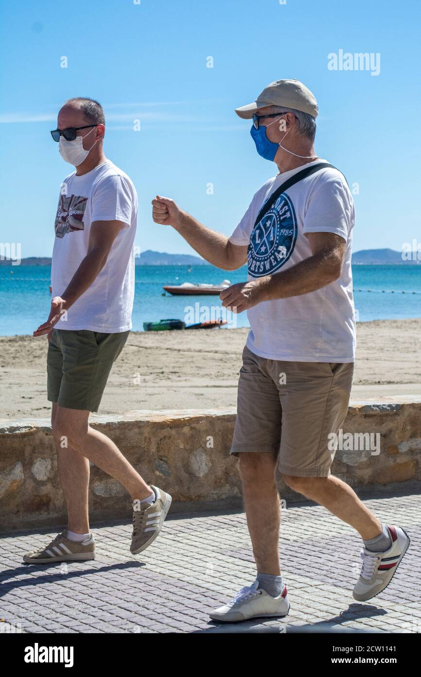 Deux hommes masque de visage de waring marchent le long de la promenade à Los Alcazares à Murcie Espagne Banque D'Images