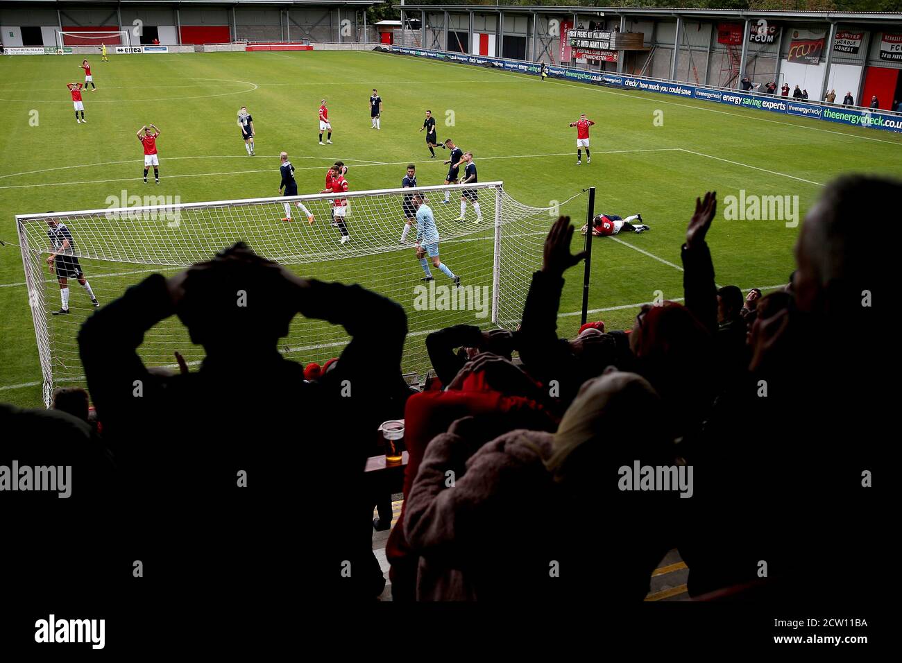 Une vue générale de l'action du match comme les supporters regardent sur les tribunes pendant la division Premier League du nord à Broadhurst Park, Manchester. Banque D'Images