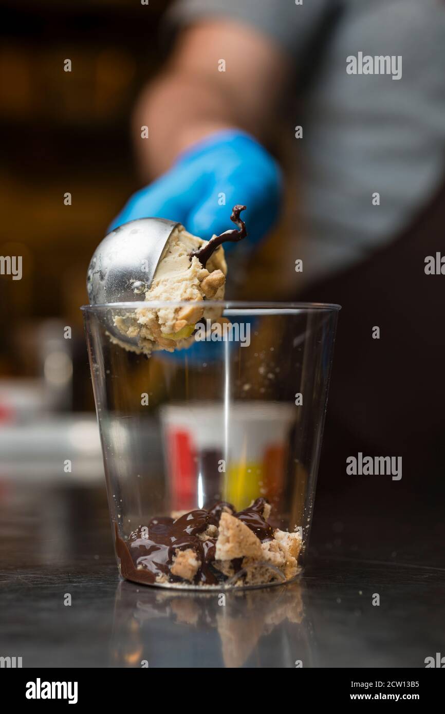 Préparation artisanale d'une tasse de verre de noix et de grains, glace italienne glace glace glace glace à la crème fouettée et biscuits à la langue du chat. Banque D'Images