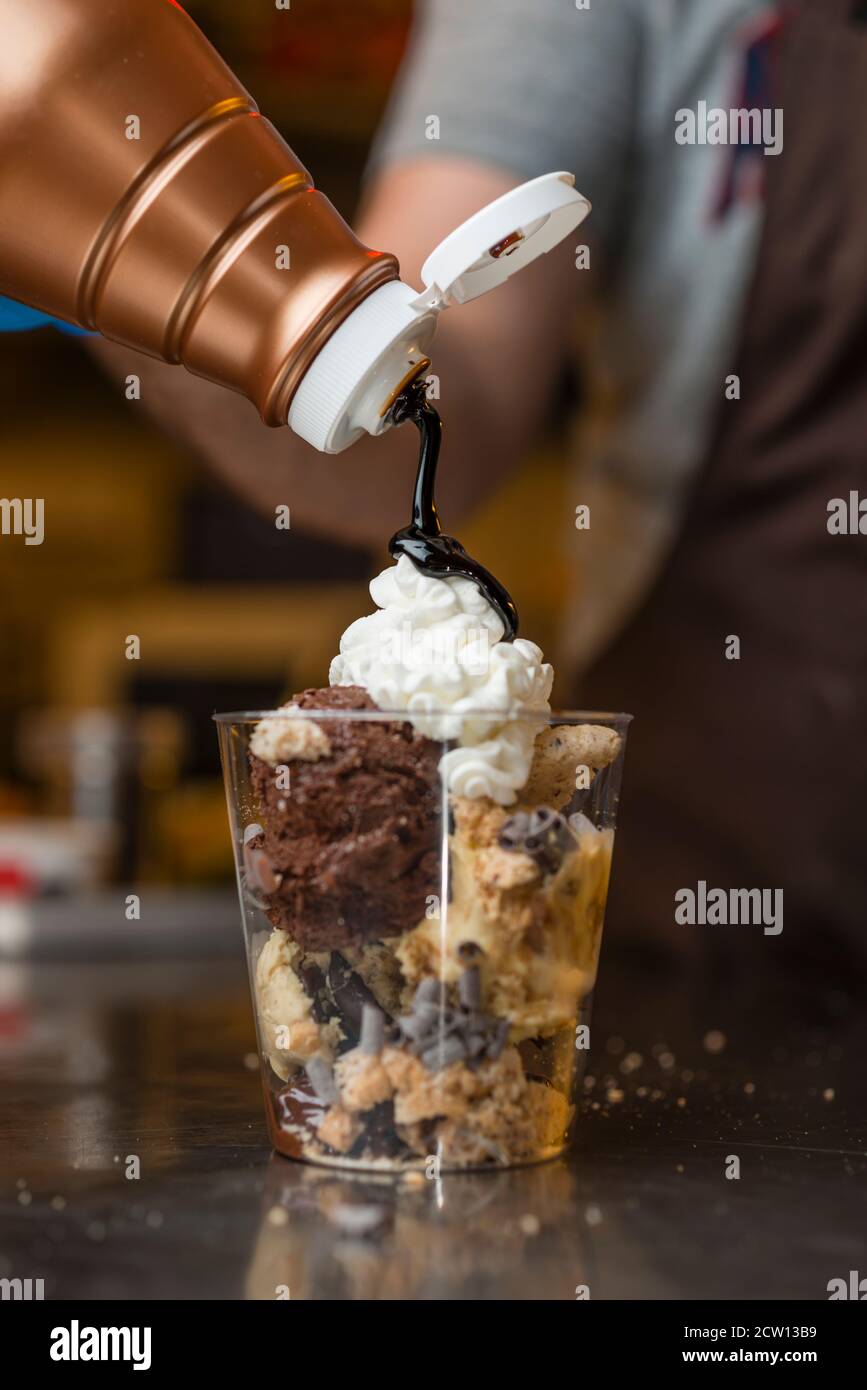 Préparation artisanale d'une tasse de verre de noix et de grains, glace italienne glace glace glace glace à la crème fouettée et biscuits à la langue du chat. Banque D'Images