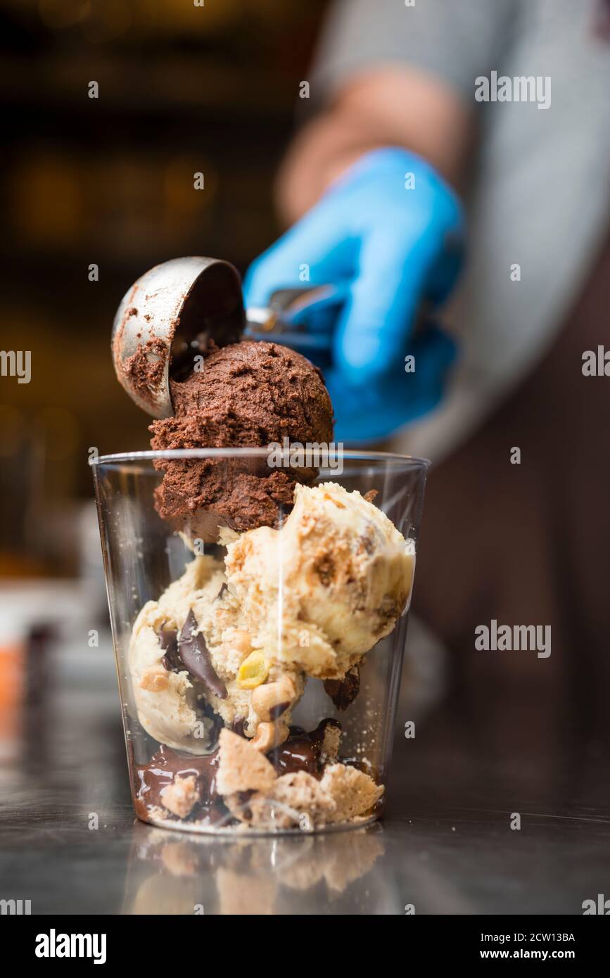 Préparation artisanale d'une tasse de verre de noix et de grains, glace italienne glace glace glace glace à la crème fouettée et biscuits à la langue du chat. Banque D'Images