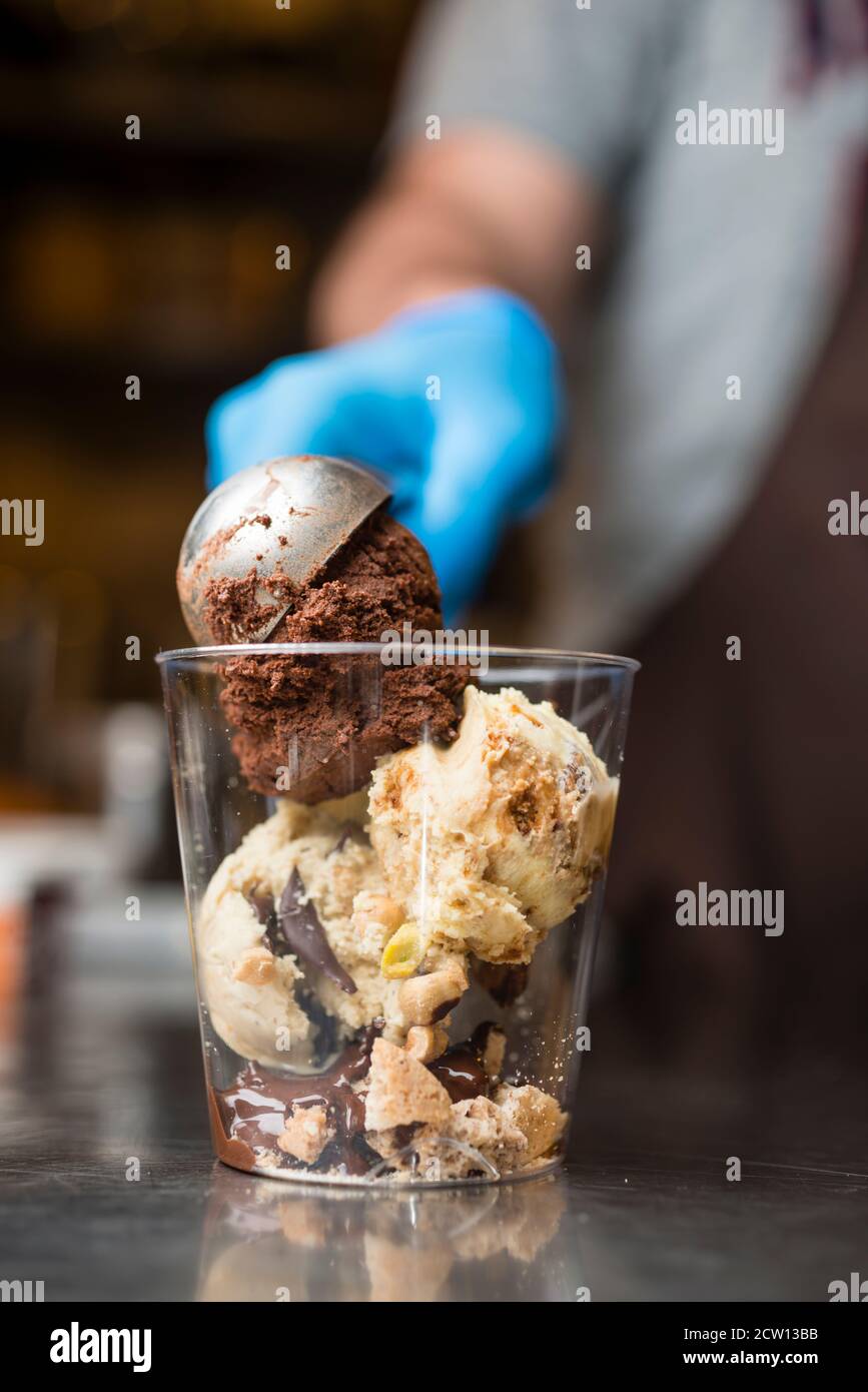 Préparation artisanale d'une tasse de verre de noix et de grains, glace italienne glace glace glace glace à la crème fouettée et biscuits à la langue du chat. Banque D'Images