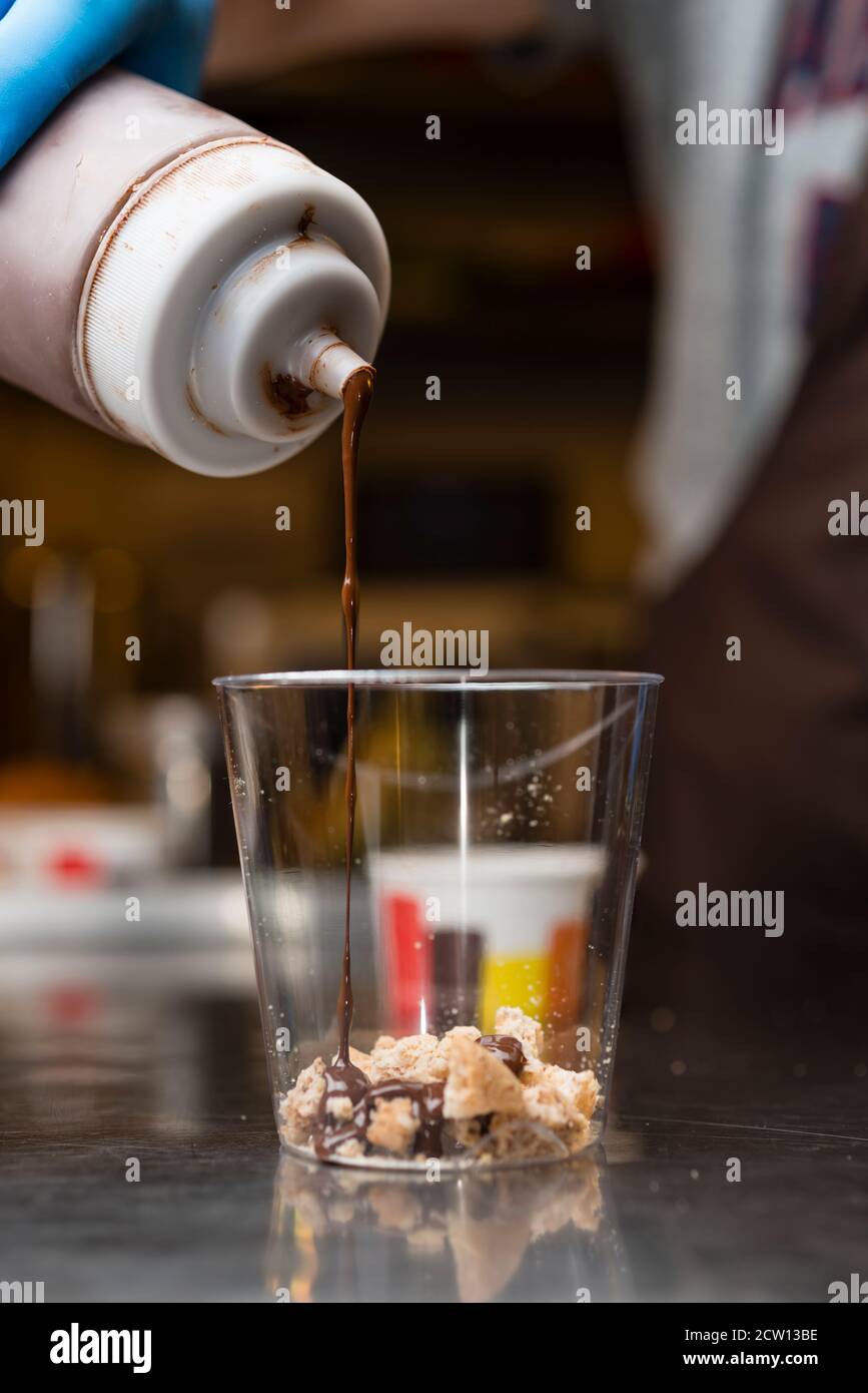 Préparation artisanale d'une tasse de verre de noix et de grains, glace italienne glace glace glace glace à la crème fouettée et biscuits à la langue du chat. Banque D'Images