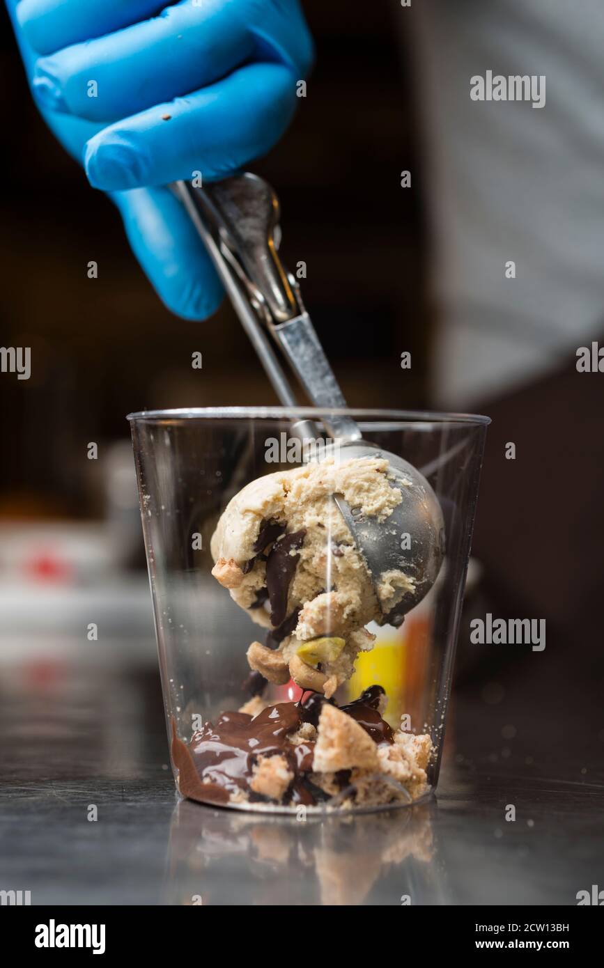 Préparation artisanale d'une tasse de verre de noix et de grains, glace italienne glace glace glace glace à la crème fouettée et biscuits à la langue du chat. Banque D'Images