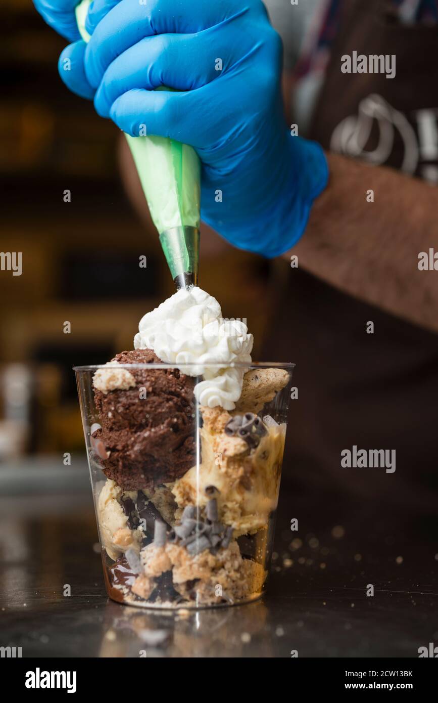 Préparation artisanale d'une tasse de verre de noix et de grains, glace italienne glace glace glace glace à la crème fouettée et biscuits à la langue du chat. Banque D'Images