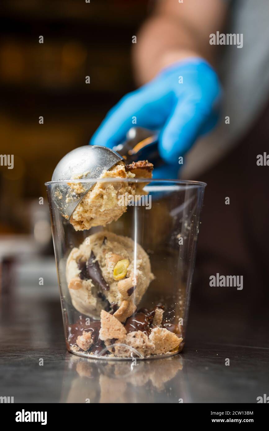 Préparation artisanale d'une tasse de verre de noix et de grains, glace italienne glace glace glace glace à la crème fouettée et biscuits à la langue du chat. Banque D'Images