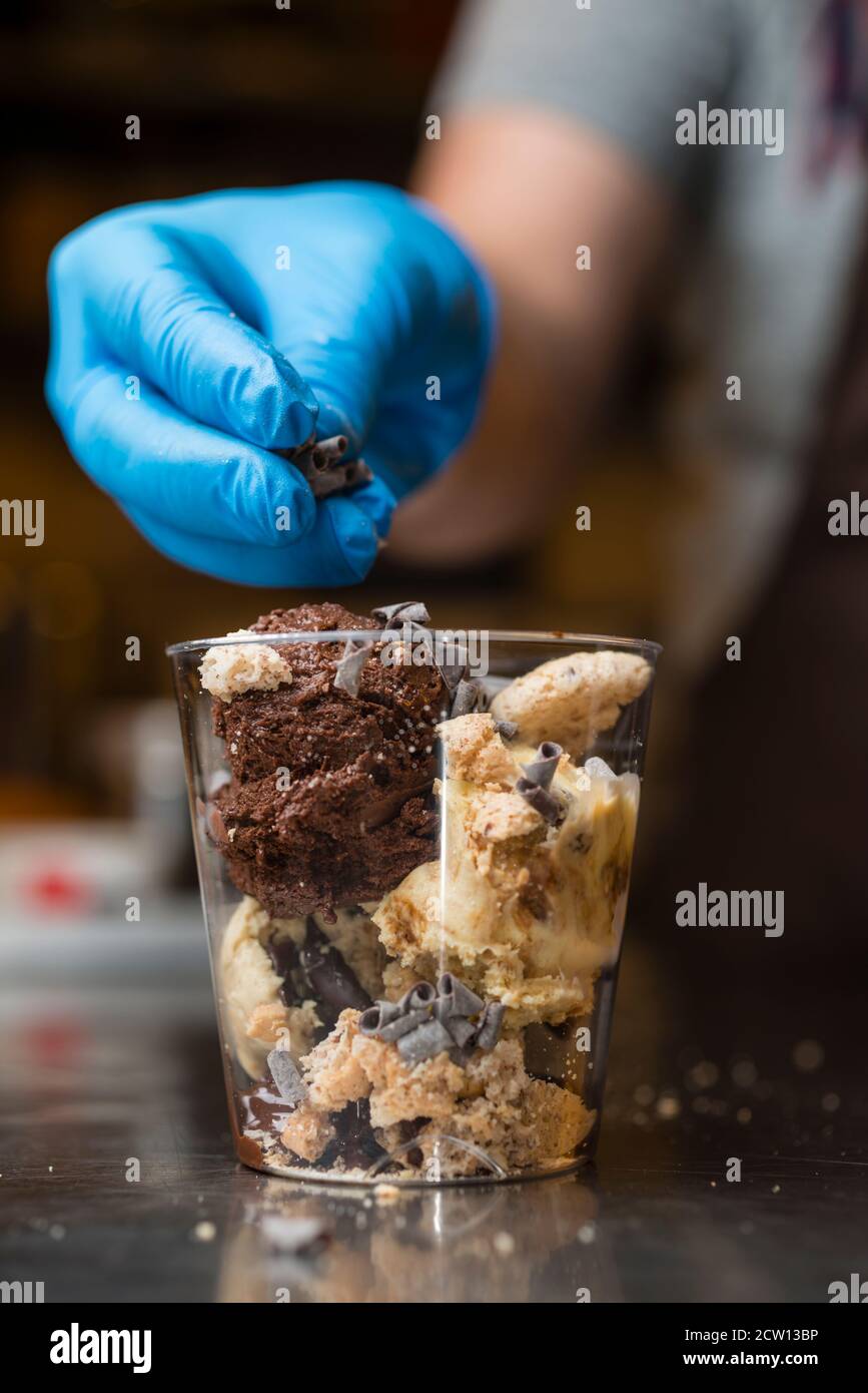 Préparation artisanale d'une tasse de verre de noix et de grains, glace italienne glace glace glace glace à la crème fouettée et biscuits à la langue du chat. Banque D'Images