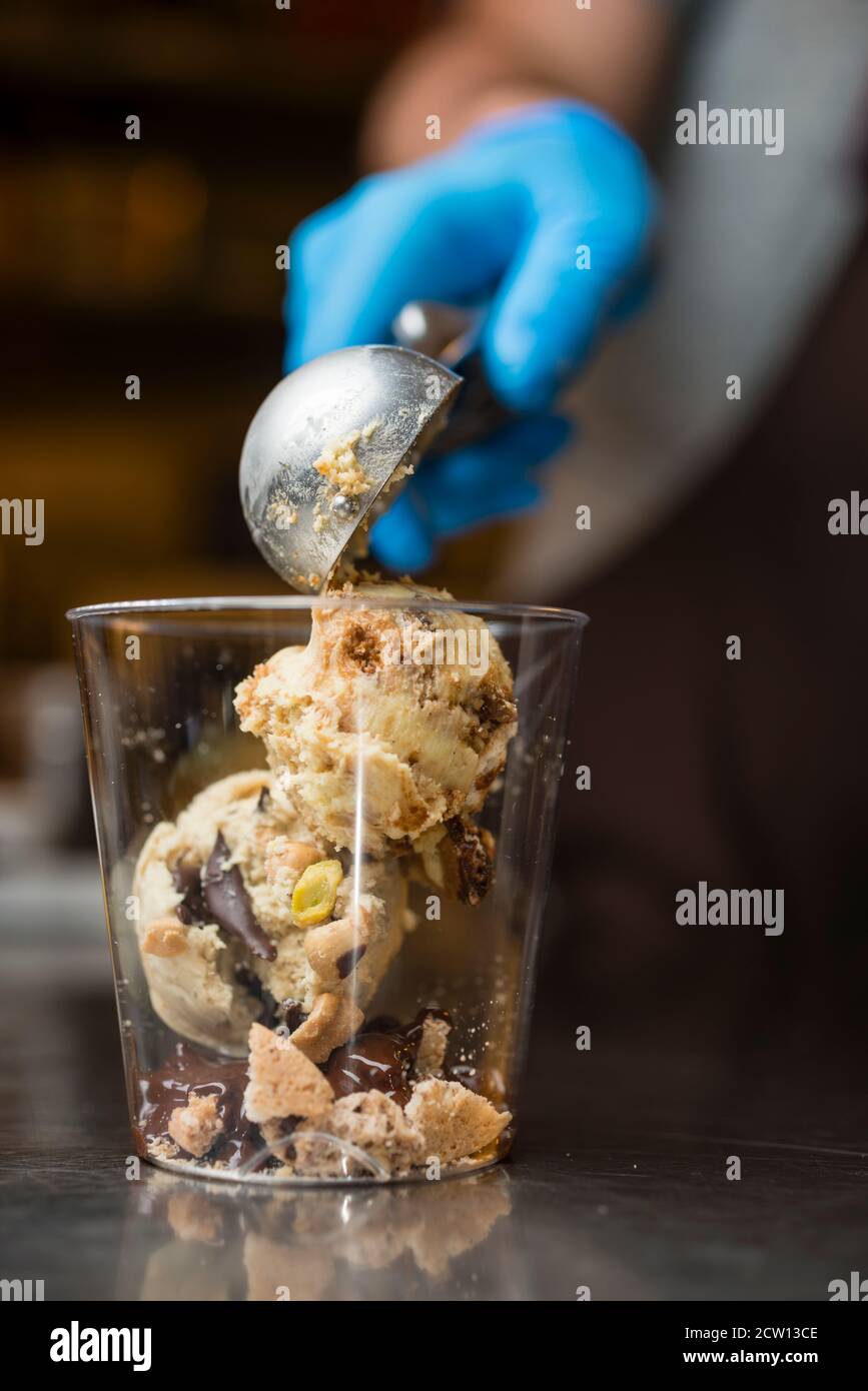 Préparation artisanale d'une tasse de verre de noix et de grains, glace italienne glace glace glace glace à la crème fouettée et biscuits à la langue du chat. Banque D'Images