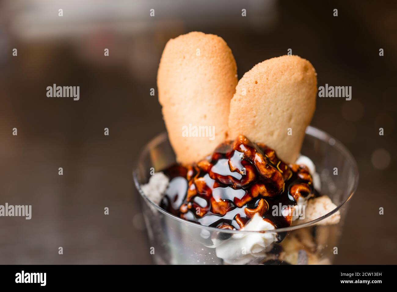 Préparation artisanale d'une tasse de verre de noix et de grains, glace italienne glace glace glace glace à la crème fouettée et biscuits à la langue du chat. Banque D'Images