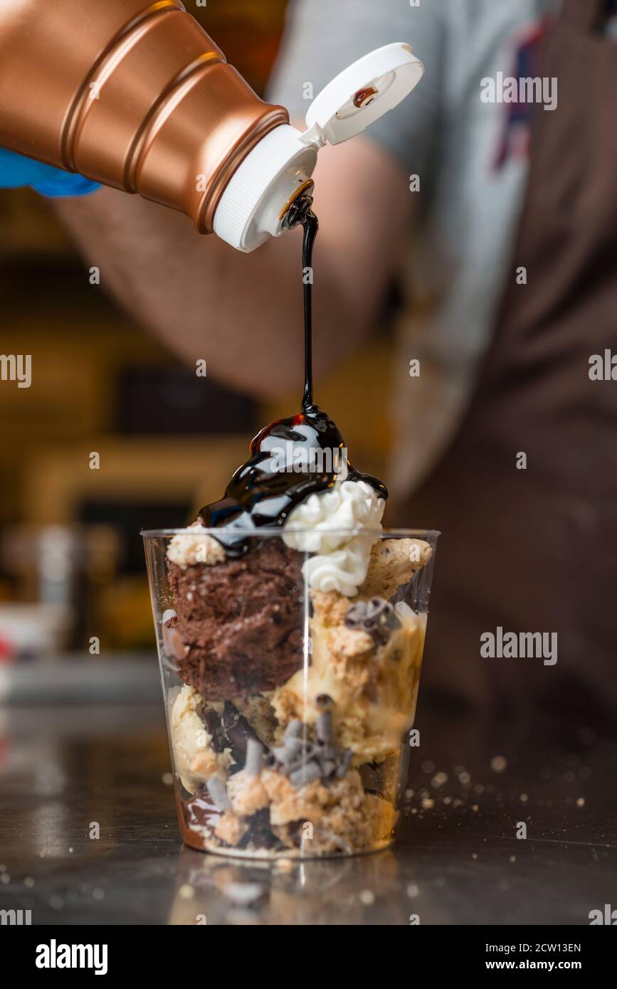 Préparation artisanale d'une tasse de verre de noix et de grains, glace italienne glace glace glace glace à la crème fouettée et biscuits à la langue du chat. Banque D'Images