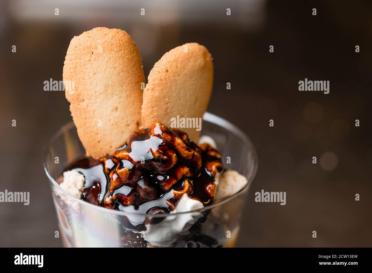 Préparation artisanale d'une tasse de verre de noix et de grains, glace italienne glace glace glace glace à la crème fouettée et biscuits à la langue du chat. Banque D'Images