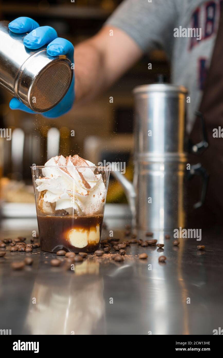 Préparation artisanale d'une tasse de glace italienne glace glace galato affogato noyée dans un café expresso avec de la crème fouettée et des biscuits à la langue du chat. Banque D'Images