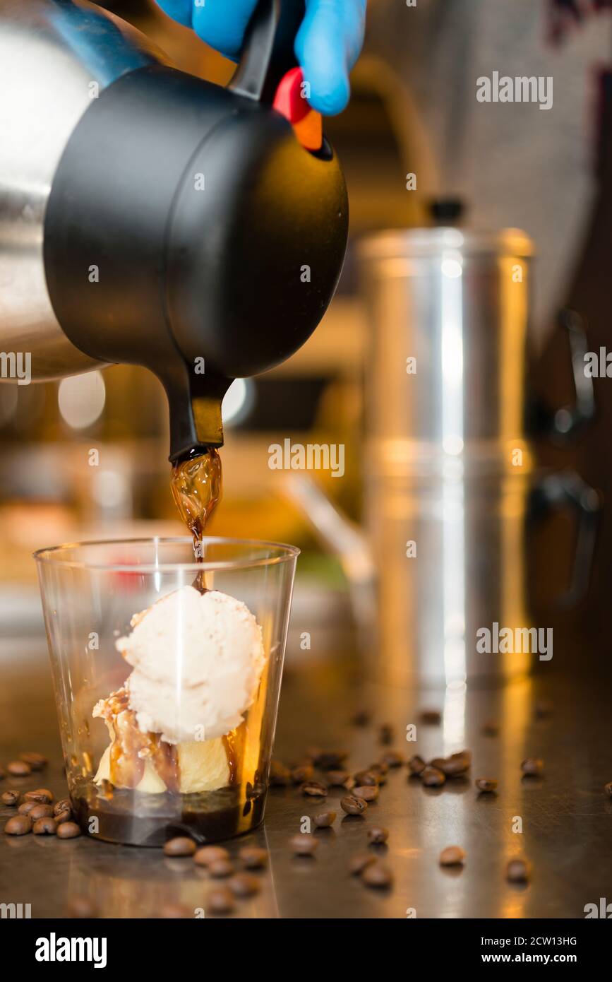 Préparation artisanale d'une tasse de glace italienne glace glace galato affogato noyée dans un café expresso avec de la crème fouettée et des biscuits à la langue du chat. Banque D'Images
