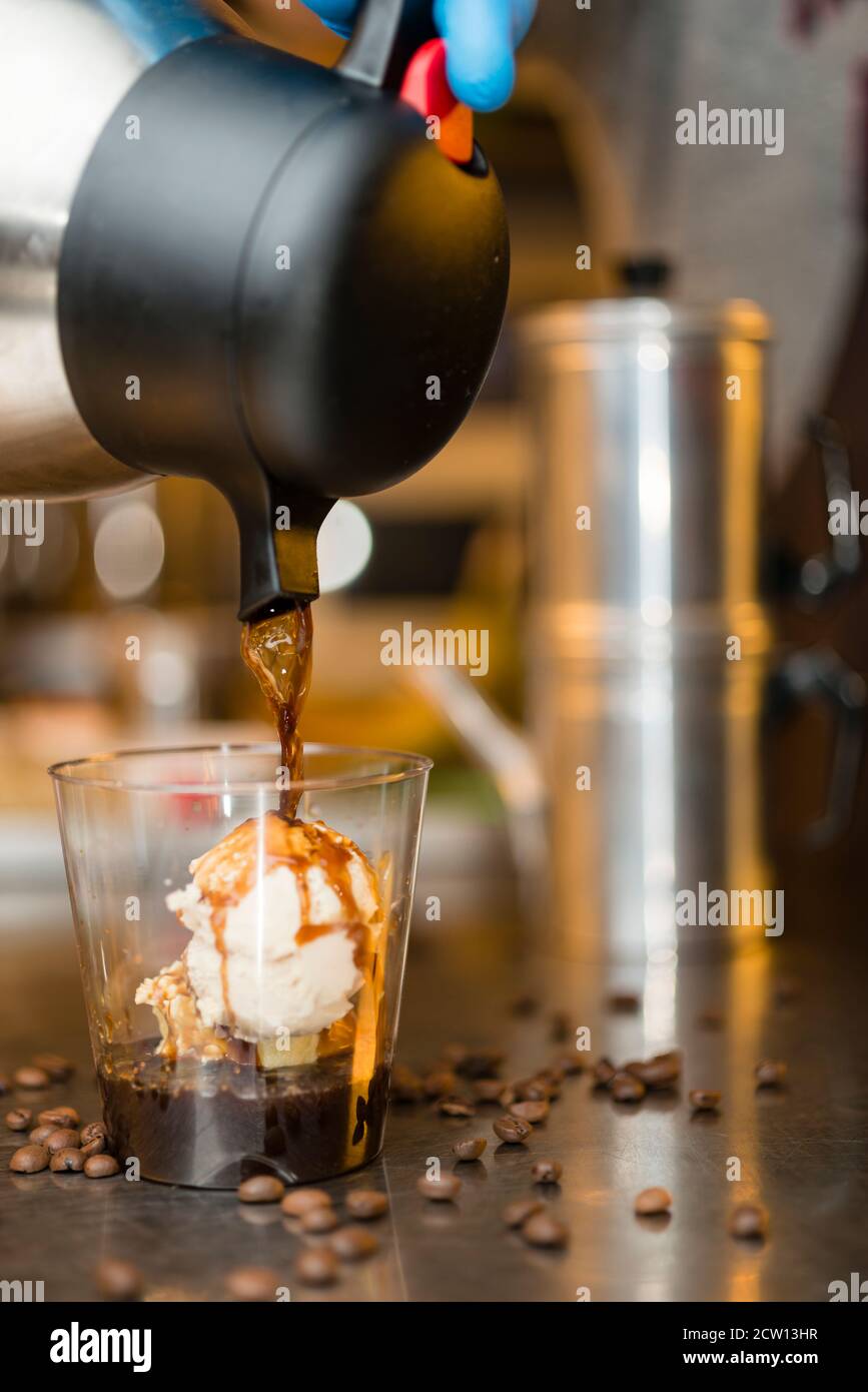 Préparation artisanale d'une tasse de glace italienne glace glace galato affogato noyée dans un café expresso avec de la crème fouettée et des biscuits à la langue du chat. Banque D'Images