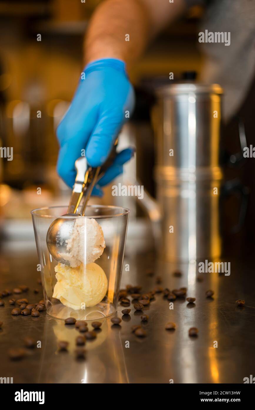 Préparation artisanale d'une tasse de glace italienne glace glace galato affogato noyée dans un café expresso avec de la crème fouettée et des biscuits à la langue du chat. Banque D'Images