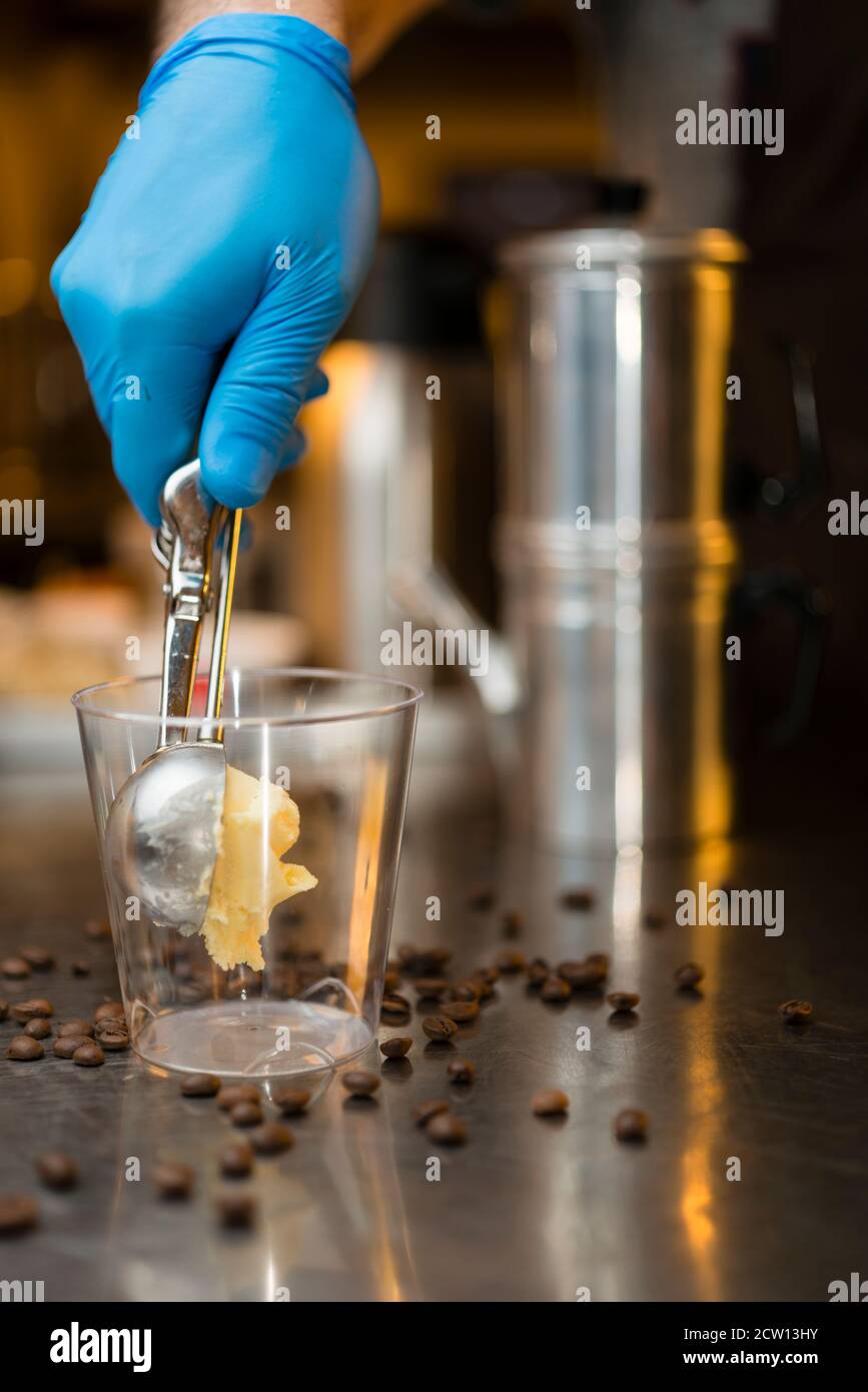 Préparation artisanale d'une tasse de glace italienne glace glace galato affogato noyée dans un café expresso avec de la crème fouettée et des biscuits à la langue du chat. Banque D'Images