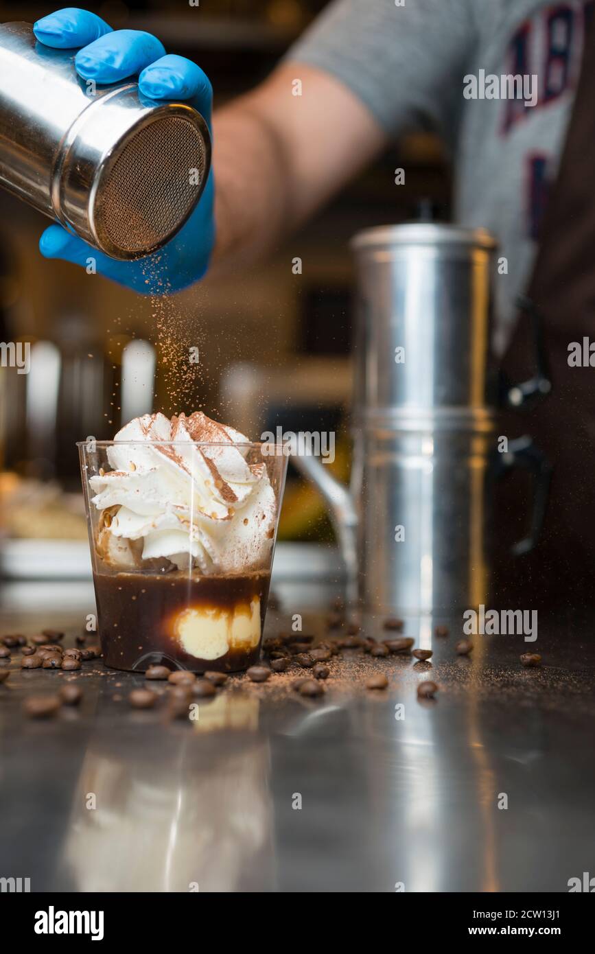 Préparation artisanale d'une tasse de glace italienne glace glace galato affogato noyée dans un café expresso avec de la crème fouettée et des biscuits à la langue du chat. Banque D'Images