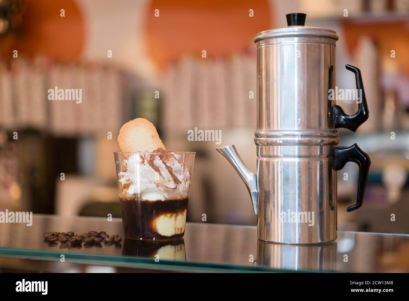 Préparation artisanale d'une tasse de glace italienne glace glace galato affogato noyée dans un café expresso avec de la crème fouettée et des biscuits à la langue du chat. Banque D'Images