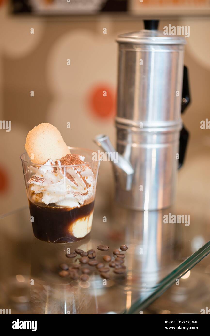 Préparation artisanale d'une tasse de glace italienne glace glace galato affogato noyée dans un café expresso avec de la crème fouettée et des biscuits à la langue du chat. Banque D'Images